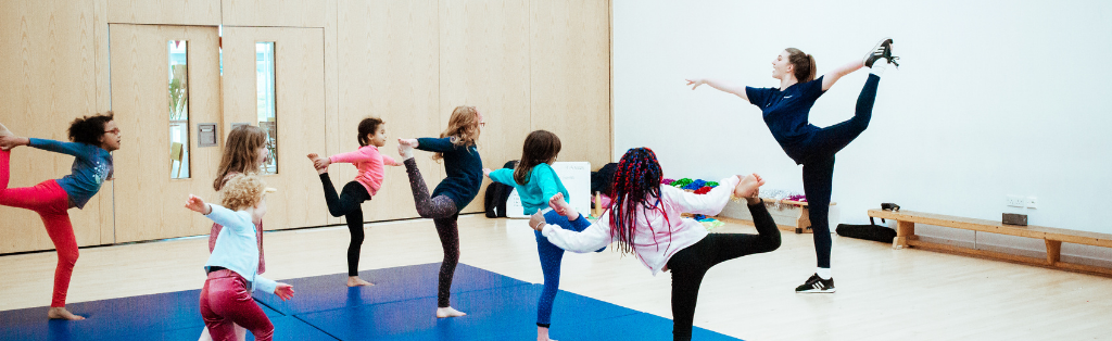 Reimagining PE in Schools 2 Premier Education coach teaching children to do gymnastics in a school PE session.