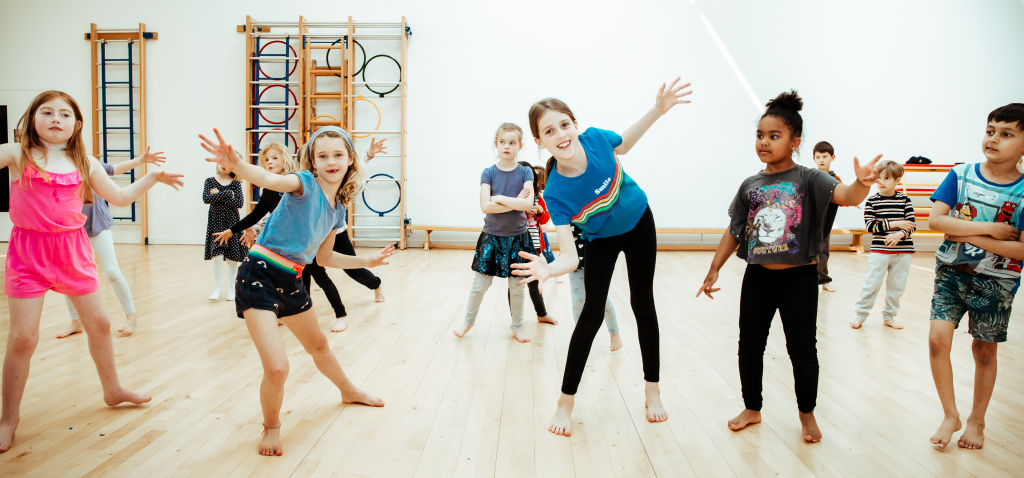 Is Dance a Sport? The Benefits for Kids 4 Pupils doing jazz hands during a dance class