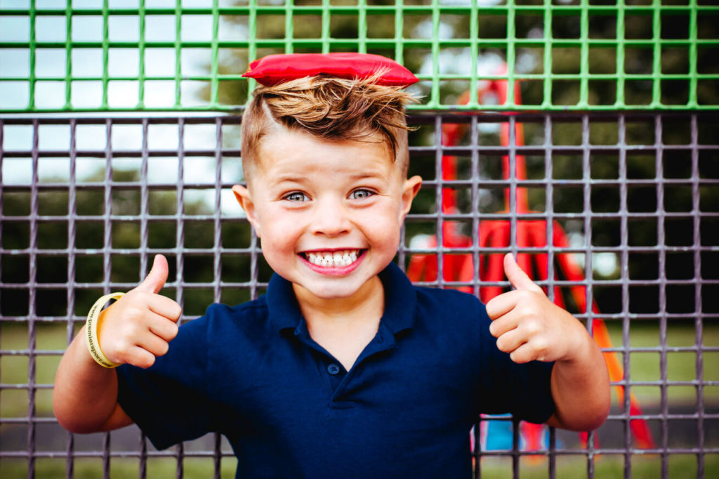 5 games to make walking with children more fun 2 A child grinning with two thumbs up in the outdoors