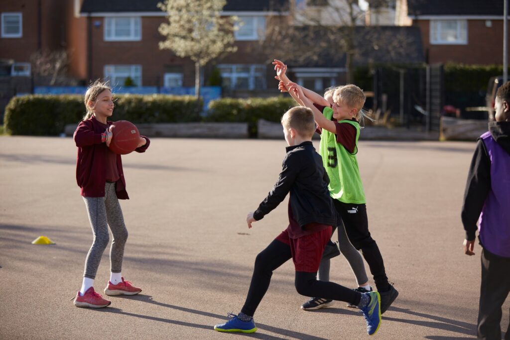 Children throwing and catching a ball in pe
