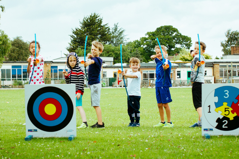 Movement and Mood: Why Active Kids Thrive 2 Happy children doing archery at a holiday club.